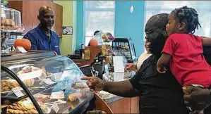  ??  ?? A Bite 2 Eat Soul Food Grill and Catering co-owner Anthony King (left) chats with customers James Shelton Jr. and grandson James Shelton IV at the Boynton Beach Library cafe on Tuesday.