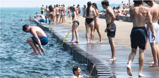  ?? ASHLEE REZIN GARCIA/SUN-TIMES ?? Officially, Chicago’s beaches remain closed. But with temperatur­es in the 90s again, that mayoral order didn’t stop these people from jumping into Lake Michigan from this spot along the Lakefront Trail near West Diversey Parkway on Monday afternoon.