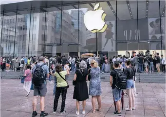  ?? | AP ?? FOREIGN tourists watch people queue in line to enter the Apple Store for the debut of the latest iPhones in Shanghai, China. China raised tariffs yesterday on thousands of US goods in an escalation of its fight with President Donald Trump over technology policy.