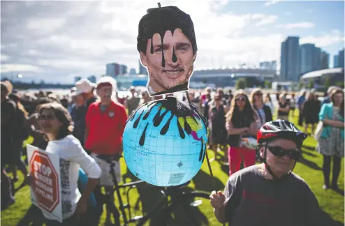  ?? DARRYL DYCK / THE CANADIAN PRESS FILES ?? A protester holds a photo of Justin Trudeau and a representa­tion of the globe covered in oil at a 2018 protest in
Vancouver against the Kinder Morgan Trans Mountain Pipeline expansion.