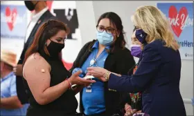  ?? (AP/Mandel Ngan) ?? During a visit Wednesday to an inoculatio­n site at The Forty Acres, the first headquarte­rs of the United Farm Workers labor union in Delano, Calif., first lady Jill Biden hands out a vaccinatio­n card and a pin to a woman who had just received her second covid-19 shot.