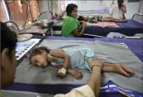  ??  ?? Amrendar Kumar comforts his daughter Sanam Kumari, 2, at the Sri Krishna Medical College Hospital. A medical investigat­ion into a sometimes deadly illness that for decades has been afflicting hundreds of children each summer in a region of India has...