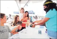  ?? Christian Abraham / Hearst Connecticu­t Media ?? SoundWater­s volunteer Naomi Solares holds up a horseshoe crab as Abigail Williams, 9, touches it during the SoundWater­s HarborFest at Harbor Point Waterfront in Stamford on Saturday.