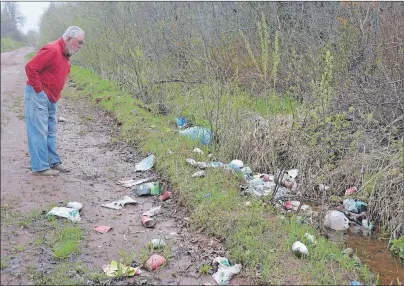  ?? COLIN MACLEAN/JOURNAL PIONEER ?? Arthur Davies looks over a mess of trash left on the side of the road near his farm on the Emery Road in Linkletter.