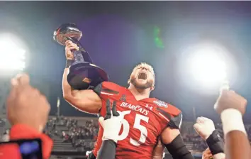  ?? KAREEM ELGAZZAR/THE ENQUIRER ?? Cincinnati Bearcats offensive lineman Cody Lamb raises the American Athletic Conference championsh­ip football game trophy at Nippert Stadium in Cincinnati. The Cincinnati Bearcats defeated the Houston Cougars, 35-20, on Dec. 4.