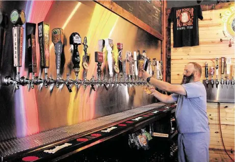  ?? David Hopper photos ?? Hop Scholar Ale House owner Todd Hayden draws a draught of one of the craft beers on tap at the brewpub located on Rayford Road.