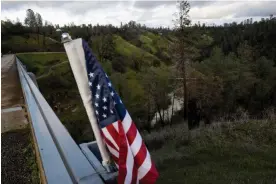  ?? ?? An American flag adorns the Shasta county Vietnam Veterans Memorial bridge. The county’s board of supervisor­s voted on 28 March to scrap voting with technology and create a new manual tally system. Photograph: Marlena Sloss