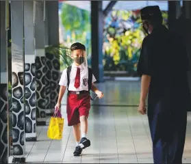  ??  ?? A staff member greets a student Monday at an elementary school in Jakarta.