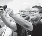  ?? NATI HARNIK/AP ?? A shareholde­r gets a selfie with the popular Buffett at the 2014 meeting.