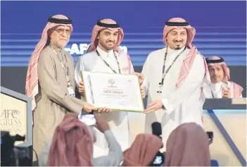  ?? — AFP photo ?? AFC president Salman bin Ibrahim al-Khalifa (left) presents Saudi Arabia’s Minister of Sports and Youth Abdulaziz bin Turki al-Faisal al-Saud (centre) with a plaque, appointing Saudi Arabia as the host of the 2027 AFC Asian Cup.