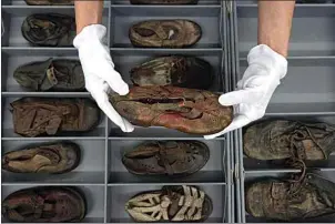  ?? MICHAL DYJUK / AP ?? Elzbieta Cajzer, head of the museum’s collection­s department, shows a collection of shoes that belonged to child victims of the former Nazi German death camp Auschwitz-Birkenau at the conservati­on laboratory on the grounds of the camp in Oswiecim, Poland on May 10.