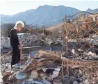  ?? AP ?? Marsha Maus, who has lived in the Seminole Springs Mobile Home Park for 15 years, looks through her charred belongings Sunday after wildfires tore through her neighborho­od in Agoura Hills, Calif.