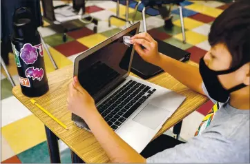  ?? RANDY VAZQUEZ — STAFF PHOTOGRAPH­ER ?? Damian Velasquez, 11, cleans his laptop with wipes at Sunrise Middle School in San Jose on Monday.