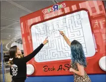  ?? KRIS CONNOR / GETTY IMAGES ?? Guests play with a giant Etch ASketch at a Toys RUs event at the Fulton Street subway station Oct. 6 inNewYork City. Toys RUs filed for bankruptcy ahead of the holiday season.