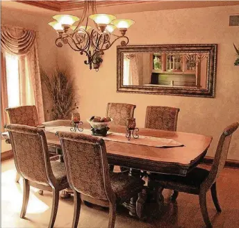  ?? CONTRIBUTE­D PHOTOS BY KATHY TYLER ?? Maple flooring enhances the dining room, which is further embellishe­d with fauxpainte­d walls and a scroll motif painted in a border above crown moldings around a backlit tray ceiling.