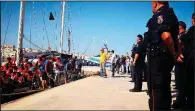  ?? AP/ANSA/ELIO DESIDERIO ?? Italian police officers watch Saturday as the rescue ship Alex docks at the island of Lampedusa with 46 migrants on board.