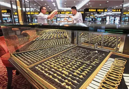  ??  ?? Safe haven: A customer choosing jewellery in one of the goldsmith shops in Petaling Jaya. The rise in gold prices has contribute­d to the growing interest in local jewellers.