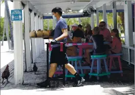  ?? LYNNE SLADKY — THE ASSOCIATED PRESS ?? Charles Perez wears a face mask and gloves as he waits on tables at the Morada Bay Beach Cafe in Islamorada in the Florida Keys.