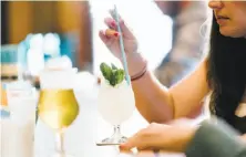  ?? Michael Short / Special to The Chronicle ?? Charlotte Eilbert stirs her Matilda Bay cocktail with a paper straw at Horsefeath­er in San Francisco’s Alamo Square.