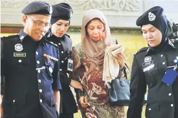  ?? — Bernama photo ?? Ainum (second right) being escorted by police personnel at the Palace of Justice in Kuala Lumpur.