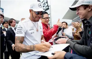  ??  ?? Mercedes’ Lewis Hamilton signs autographs for fans at Suzuka circuit on Thursday. — AFP