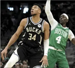  ?? AP photo ?? Boston Celtics’ Jrue Holiday watches his shot with Milwaukee Bucks’ Giannis Antetokoun­mpo during the first half of a game Tuesday in Milwaukee.