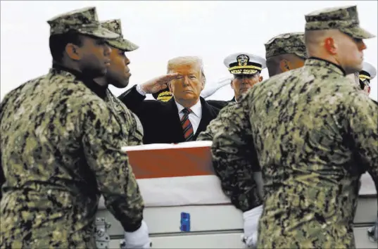  ?? Patrick Semansky The Associated Press ?? President Donald Trump salutes Saturday at Dover Air Force Base, Del., as a U.S. Navy carry team moves a transfer case containing the remains of Scott A. Wirtz, who was killed in a suicide attack in Syria.