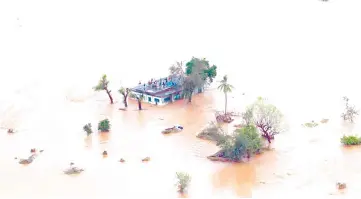  ?? — AFP photo ?? Photo shows people on a roof surrounded by flooding in an area affected by Cyclone Idai in Beira.