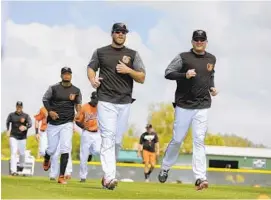  ?? LLOYD FOX/BALTIMORE SUN ?? Chris Davis, middle, and Mark Trumbo jog during the Orioles’ practice Monday in Sarasota, Fla. The club’s first spring training game is Saturday against the Twins.