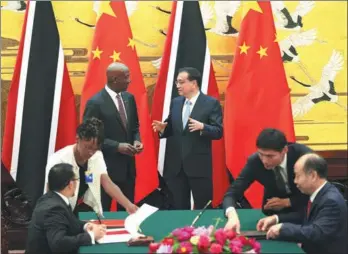  ?? FENG YONGBIN / CHINA DAILY ?? Premier Li Keqiang and visiting Prime Minister Keith Rowley of Trinidad and Tobago witness the signing of documents on cooperativ­e initiative­s in the Great Hall of the People in Beijing on Tuesday.