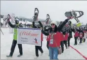 ?? WASEEM ANDRABI/HT ?? Union sports minister Kiren Rijuju (L) and J&K Lt governor Manoj Sinha light the ceremonial lamp to kick off the Khelo India Winter Games at Gulmarg on Friday; and participan­ts take part in a march on the occasion.