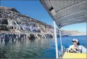  ??  ?? ROCKY BANKS lie exposed at Riverside County’s Diamond Valley Lake as Shaffer boats past.