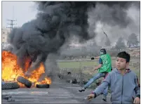  ?? "1 1)050 ?? Two Palestinia­n protesters use slingshots during clashes with Israeli troops following protests against U.S. President Donald Trump’s decision to recognize Jerusalem as the capital of Israel, in the West Bank city of Ramallah, Friday.