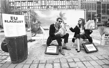  ?? — AFP photo ?? Oxfam activists stage a satirical street-play mimicking wealthy people hidding their money in tax haven, on December 5, near the European institutio­ns in Brussels, within a meeting of EU ministers over a credible blacklist of non-EU tax havens.