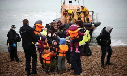  ?? Photograph: Henry Nicholls/Reuters ?? People who crossed the Channel in a small boat are helped ashore by RNLI and Border Force staff at Dungeness in Kent on 24 November.