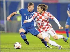  ?? AP PHOTO ?? Iceland’s Aron Gunnarsson, left, is challenged by Croatia’s Luka Modric during their World Cup qualifying playoff second leg soccer match in Zagreb, Croatia.