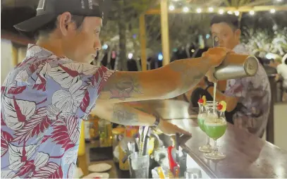  ??  ?? NIGHTLIFE FUN: The entrance, right, to the Phu Quoc Night Market. A bartender, above, mixes a cocktail at the Sunset Beach bar on the Vietnamese island of Phu Quoc.