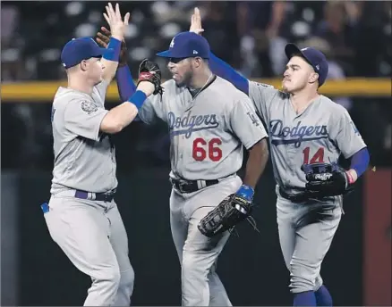  ?? Photograph­s by David Zalubowski Associated Press ?? OUTFIELDER­S Yasiel Puig (66), Enrique Hernandez (14) and Joc Pederson celebrate after the Dodgers’ victory at Coors Field.