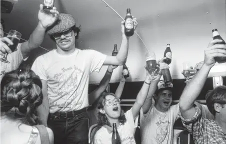  ?? Staff file photo ?? Scott Birdwell, standing left, joins in toasting the legalizati­on of homebrewin­g in Texas in 1983. DeFalco’s closure is a big loss for homebrewer­s, including hundreds of Ethiopian and Eritrean customers who brew Tella for their religious holidays.