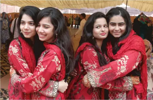  ?? AP ?? Youths in festive dresses greet each other on the occasion of the Eid al-Adha prayers in August in Lahore, Pakistan.
