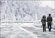  ?? AARON LYNETT / THE CANADIAN PRESS ?? A couple walk Friday near the brink of the Horseshoe Falls in Niagara Falls, Ontario, as cold weather continues through much of the province.