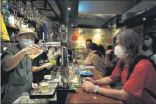  ?? KIN CHEUNG — THE ASSOCIATED PRESS ?? In this Oct. 9, 2020 photo, former lawmaker and prodemocra­cy activist Leung Kwok-hung, known as “Long Hair,” right, waits for his drink at Club 71 in Hong Kong. The bar known as a gathering place for pro-democracy activists and intellectu­als is closing. For years, the storied bar has served as a watering hole for the city’s pro-democracy activists and intellectu­als, who could freely engage in discussion­s over a round of beer or two.