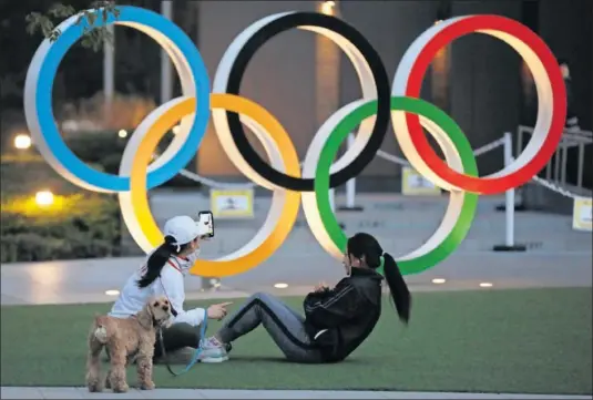  ??  ?? Dos niponas realizan ejercicio delante de los aros olímpicos que hay frente al Estadio Nacional de Tokio.