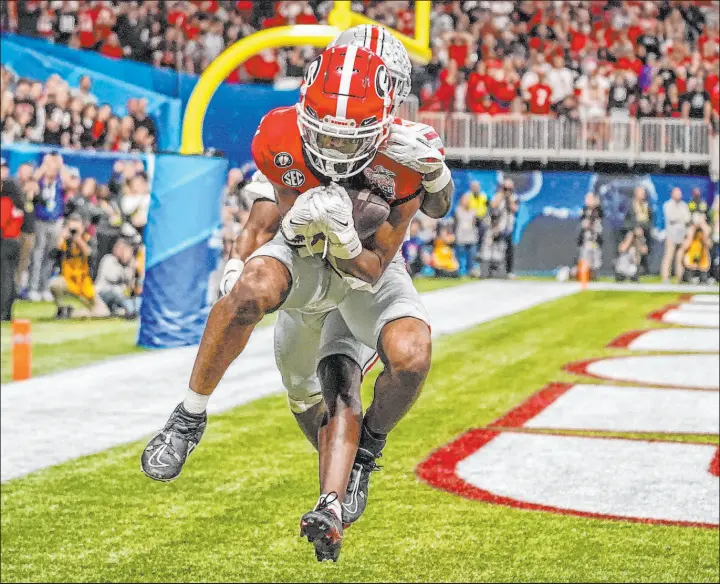  ?? Brynn Anderson The Associated Press ?? Georgia receiver Adonai Mitchell makes a go-ahead touchdown catch Saturday late in the fourth quarter against Ohio State’s Denzel Burke. The Bulldogs won 42-21.