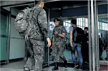  ?? CHUNG SUNG-JUN/GETTY IMAGES ?? South Korean soldiers walk through a gate in the Seoul, South Korea, railway station on Friday. The U.S. says that it will use military force if needed to stop North Korea’s nuclear missile program.