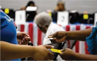  ?? PHOTOS BY REANN HUBER / REANN.HUBER@AJC.COM ?? A woman receives an “I’m a Georgia Voter” sticker Saturday after taking part in early voting at the C.T. Martin Natatorium and Recreation Center in Atlanta. Voters who participat­e in the May 22 primary have to choose a partisan ballot to vote in the...