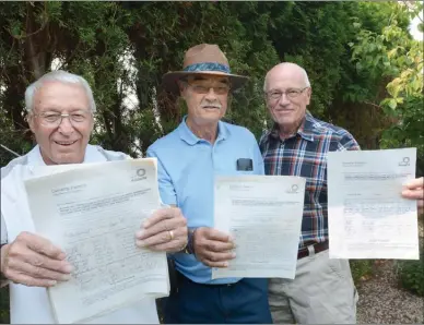  ?? GARY NYLANDER/The Daily Courier ?? From left, Ken Walker, Tony Lillington and Frank Bechard, all neighbours along Okaview Road, hold up petitions for a deer cull in the area. They are standing in front of a cedar hedge on Walker’s property that is a favourite meal for deer.