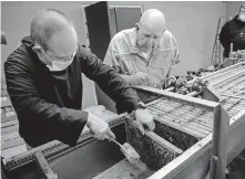  ?? [CHRIS LANDSBERGE­R PHOTOS/ THE OKLAHOMAN] ?? The Rev. Simeon Spitz, the Rev. Joachim Spexarth and Abbot Lawrence Stasyszen, from left, work to separate beeswax from honeycomb frames placed in a new honey extractor at St. Gregory's Abbey in Shawnee.