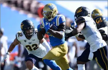  ?? AP Photo/Kelvin Kuo ?? UCLA running back Brittain Brown (center) runs the ball for a touchdown past California safety Daniel Scott (left) and Elijah Hicks during the second half of an NCAA college football game against California in Los Angeles, on Sunday. UCLA won 34-10.