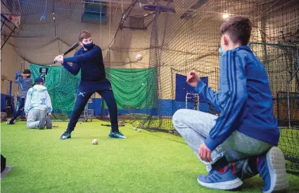  ?? EDDIE MOORE/JOURNAL ?? Fourteen-year-old Marcus Gutierrez, center, and 13-year-old Lucas Stoll, right, both from St. Michael’s High School, practice hitting during E&G Baseball Academy, which is being held at the Boys and Girls Club building in Santa Fe.